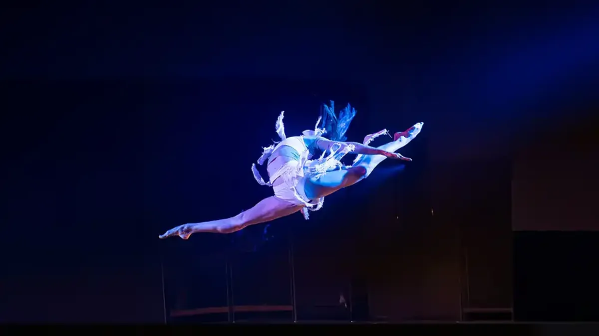 A dancer mid-leap under stage light